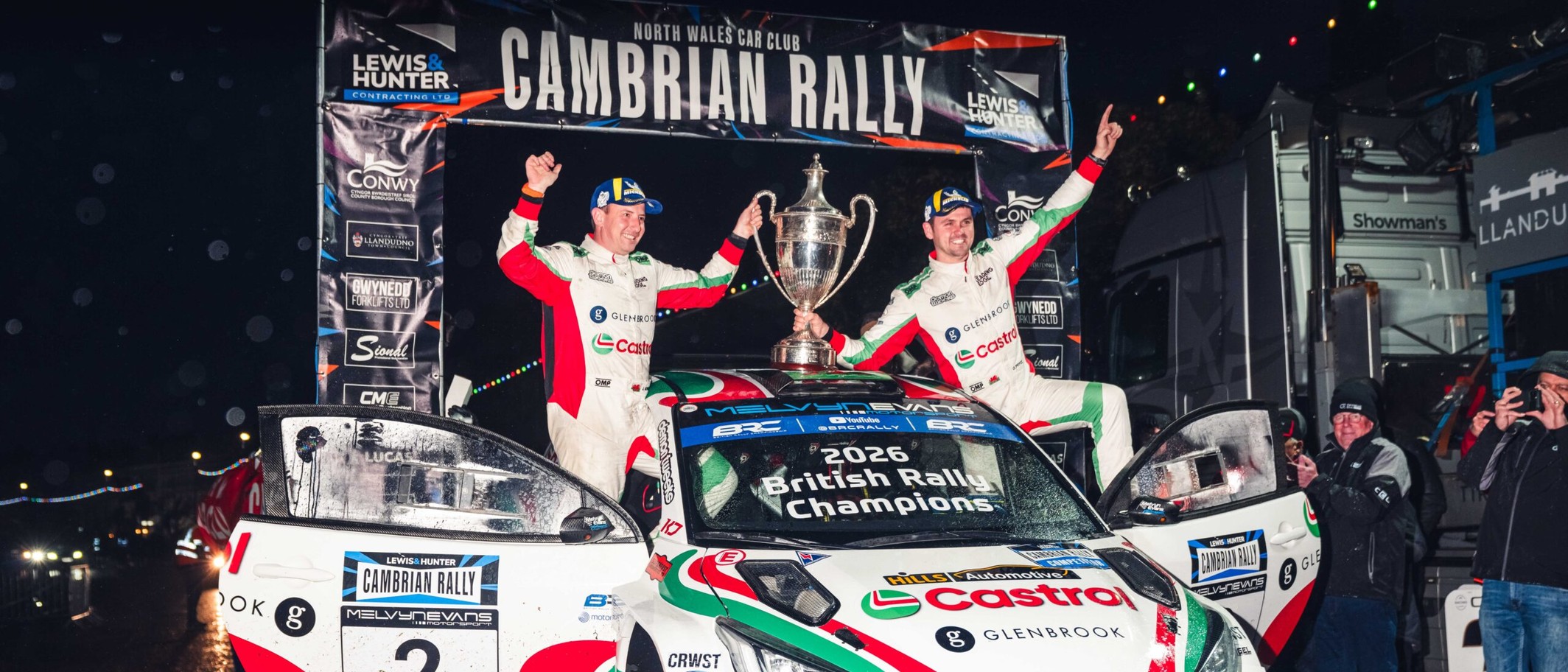 Osian Pryce and James Morgan celebrate with the trophy on the Cambrian Rally podium on 24 October 2026. Photograph: British Rally Championship.