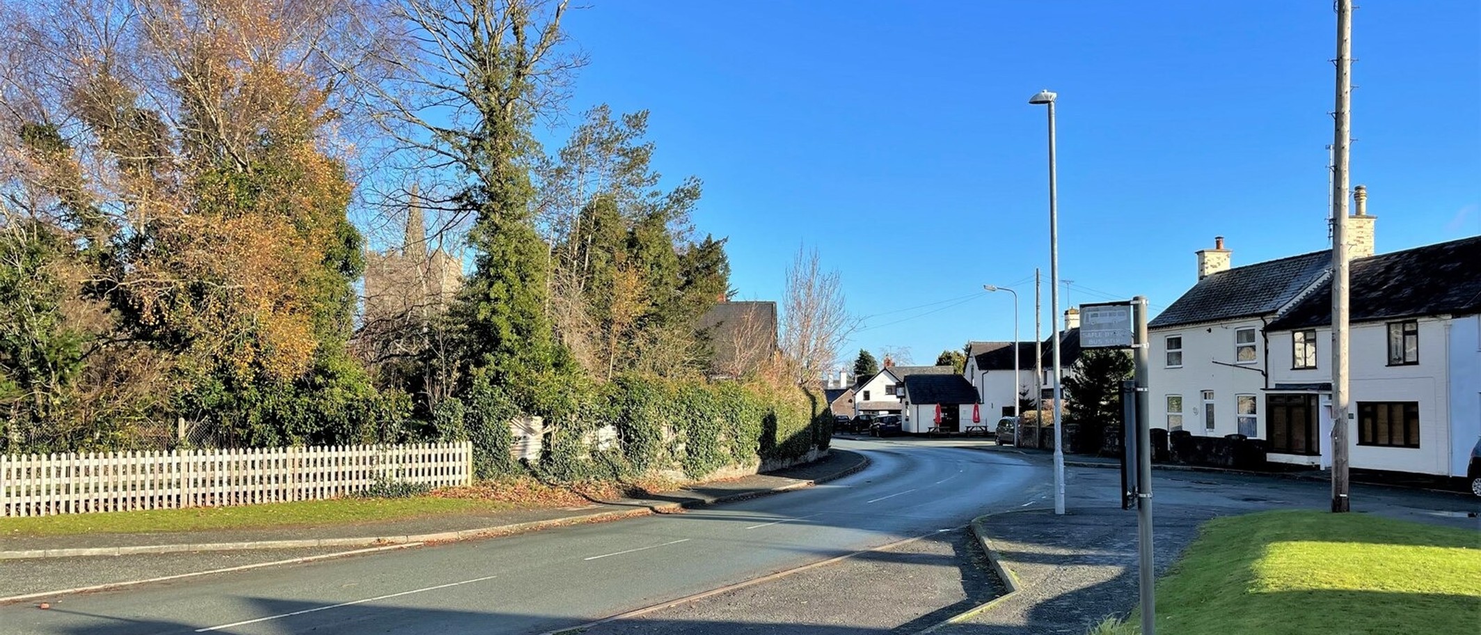 Archive: Guilsfield village and St Aelhaiarn’s church tower on 10 December 2021. General village context, not the football ground or current team. Nigel Thompson / Geograph and Wikimedia Commons, CC BY-SA 2.0; cropped.